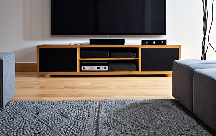 **Image Prompt:** A modern living room setup with a focus on the AV receiver as the central hub. Show multiple audio cables neatly connected to the receiver, linking various devices such as a Blu-ray player and game console. The lighting should highlight the connections and the organization of the cables.